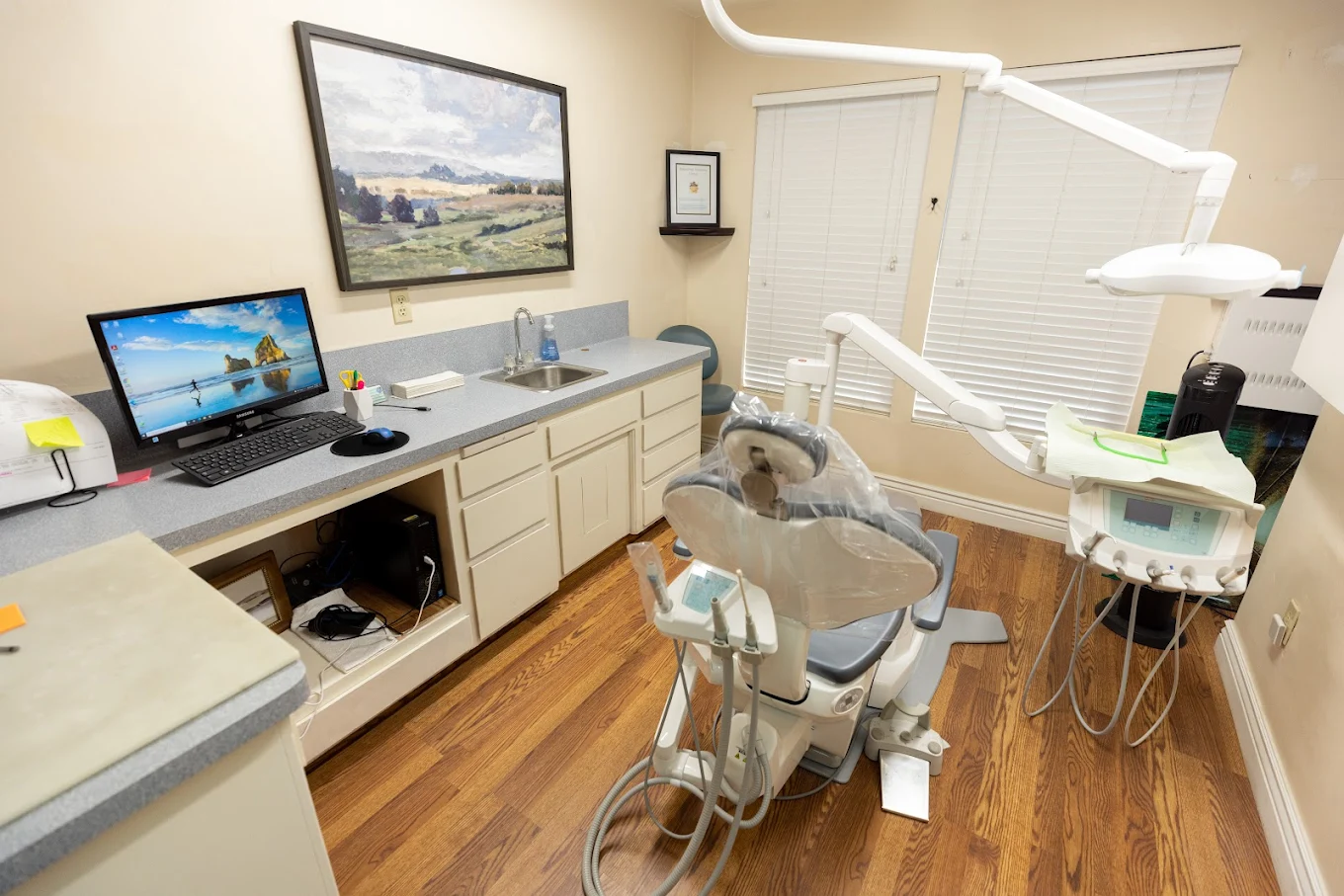 Karas Dental Care treatment room with modern dental chair, monitor and warm wood floors